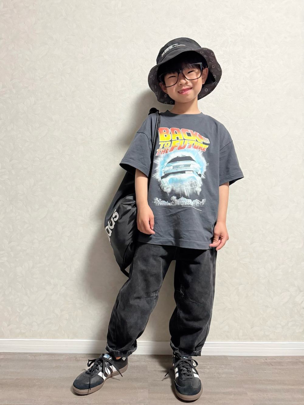 ブラック系のバックパック/リュック、ブラック系のスニーカー、グレー系のTシャツ/カットソーを着用したキッズの春コーディネートの2枚目の写真
