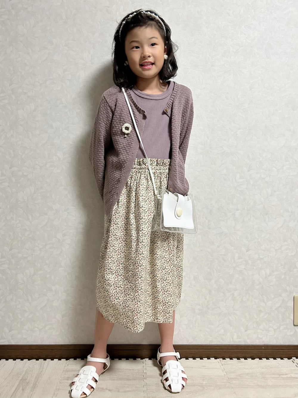パープル系のワンピース、グレー系のカーディガン/ボレロ、ホワイト系のショルダーバッグを着用したキッズの夏コーディネートの2枚目の写真