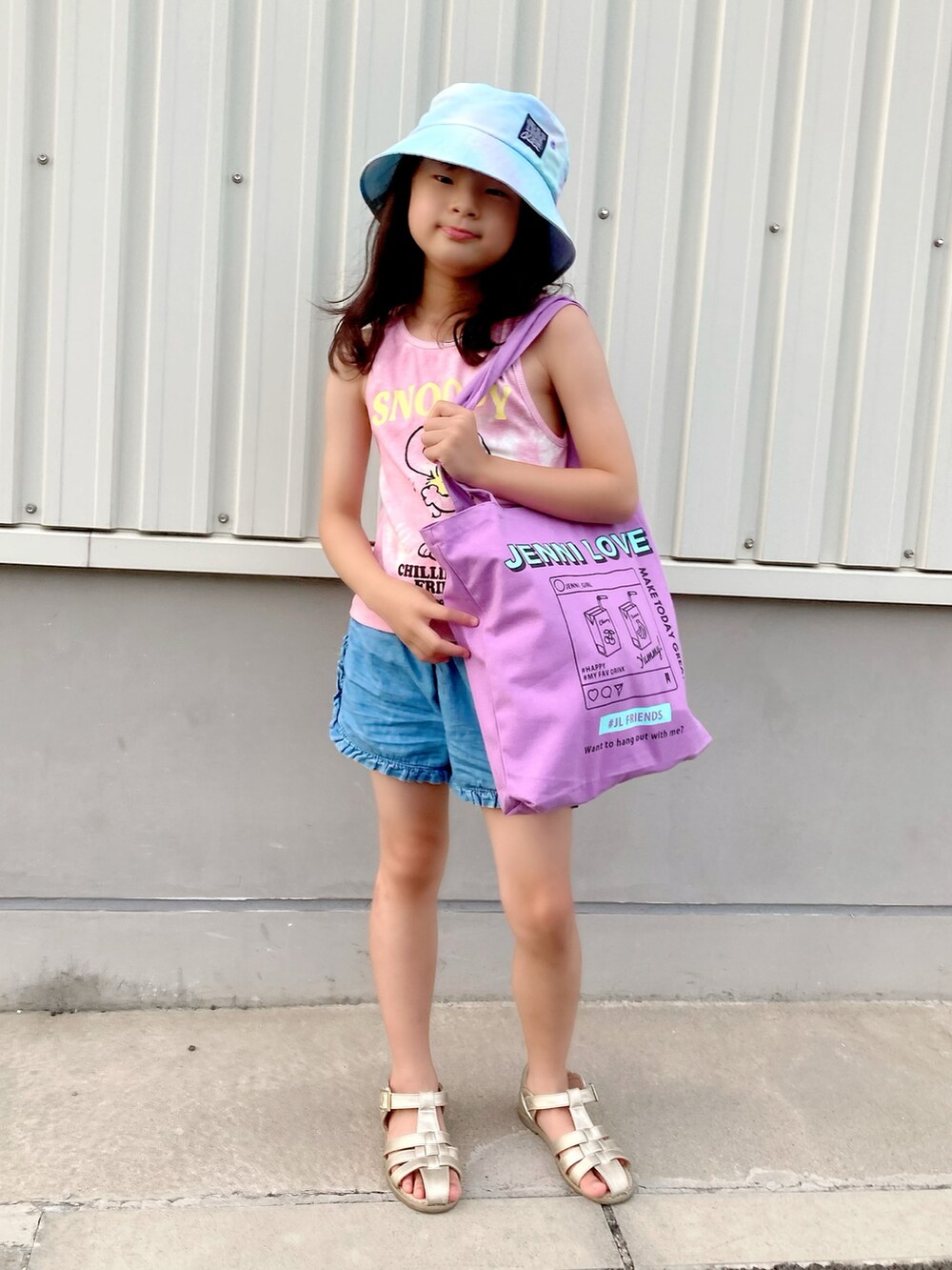 パープル系のトートバッグ、ピンク系のタンクトップ、ブルー系のパンツを着用したキッズの夏コーディネートの3枚目の写真