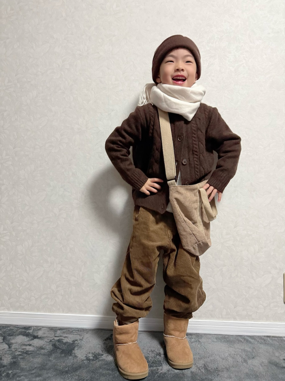 ブラウン系のカーディガン/ボレロ、ホワイト系のTシャツ/カットソー、ブラウン系のパンツを着用したキッズの冬コーディネートの3枚目の写真