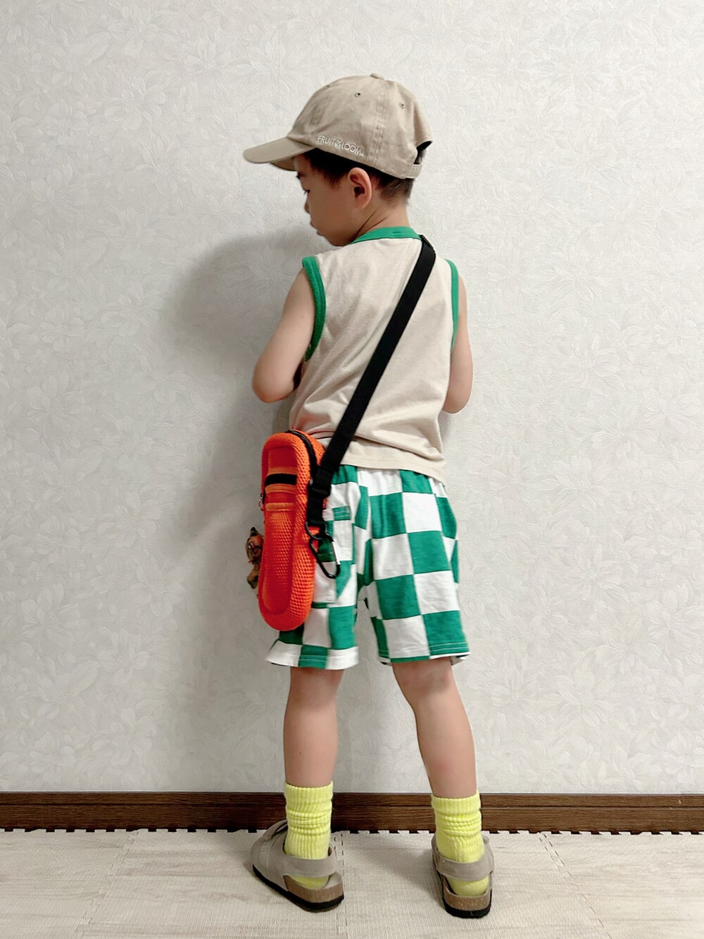 ベージュ系のタンクトップ、グリーン系のパンツ、オレンジ系のショルダーバッグを着用したキッズの夏コーディネートの4枚目の写真