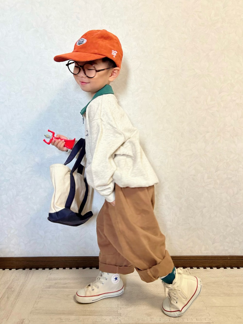 グレー系のスウェット、ブラウン系のチノパンツ、ホワイト系のショルダーバッグを着用したキッズの夏コーディネートの4枚目の写真