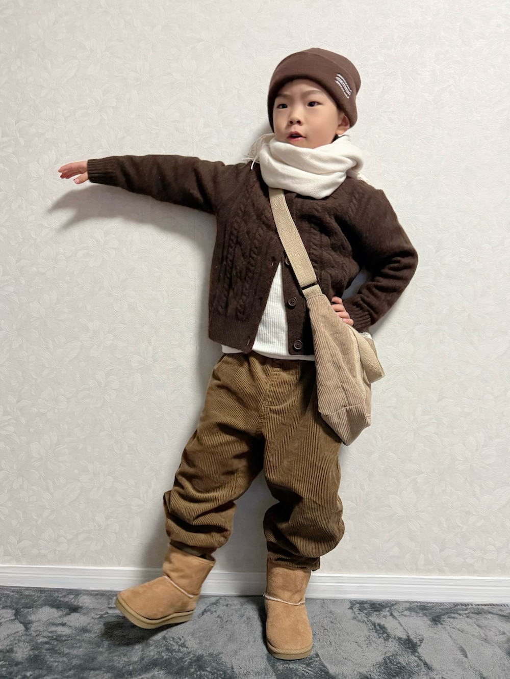 ブラウン系のカーディガン/ボレロ、ホワイト系のTシャツ/カットソー、ブラウン系のパンツを着用したキッズの冬コーディネートの4枚目の写真