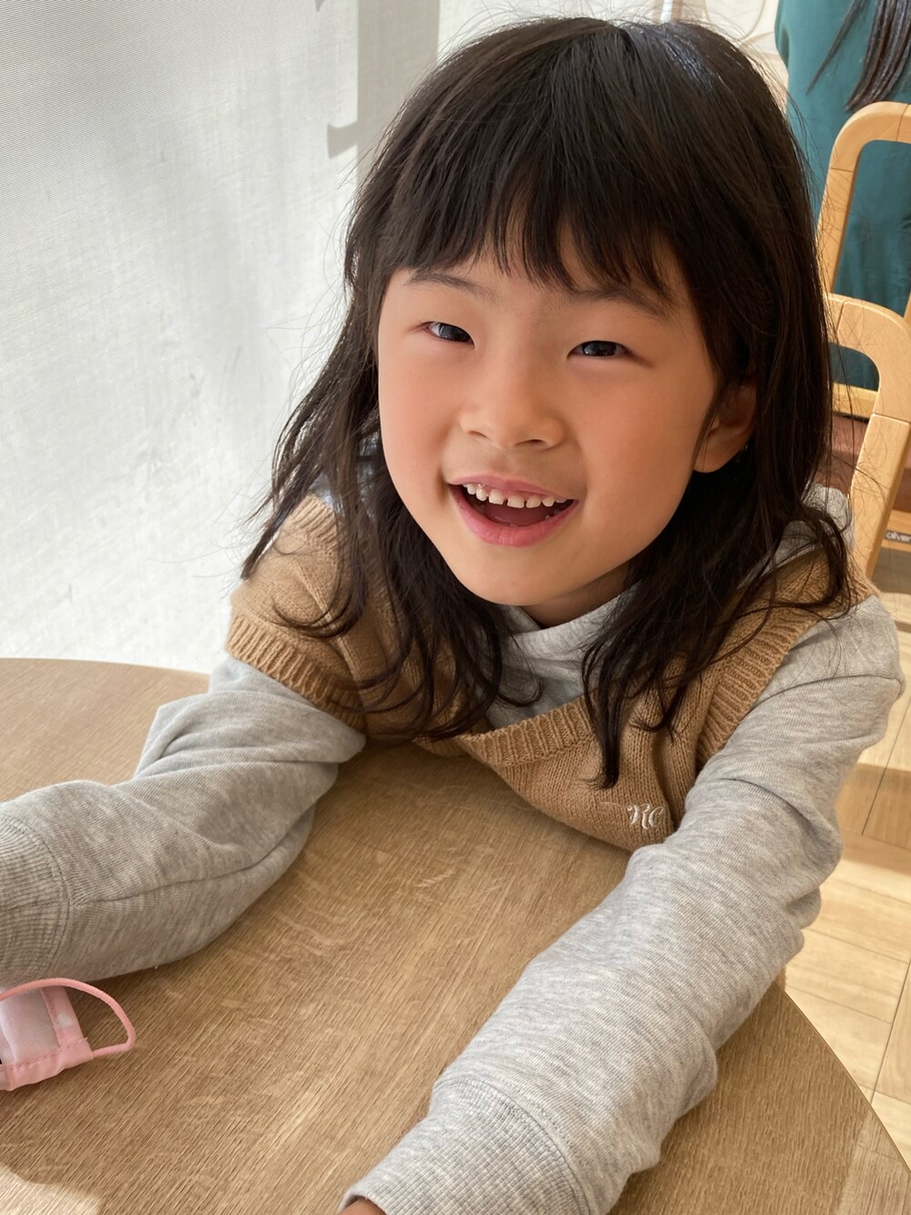 グレー系のワンピース、ベージュ系のベスト、ピンク系のショルダーバッグを着用したキッズの秋コーディネートの3枚目の写真