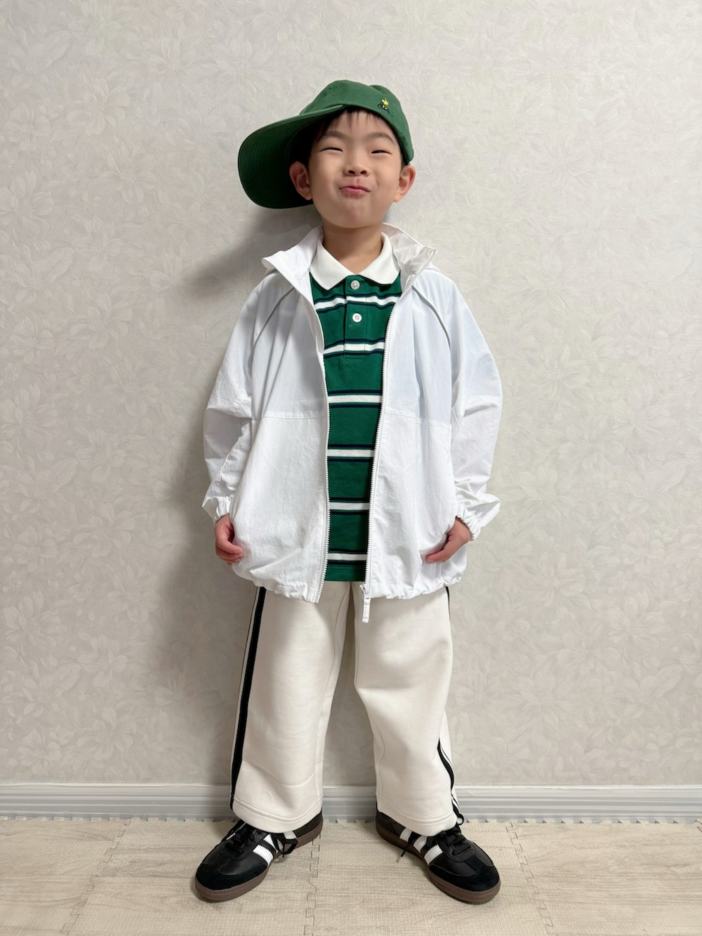 ホワイト系のナイロンジャケット、グリーン系のポロシャツ、ホワイト系のスウェットパンツを着用したキッズの冬コーディネートの2枚目の写真