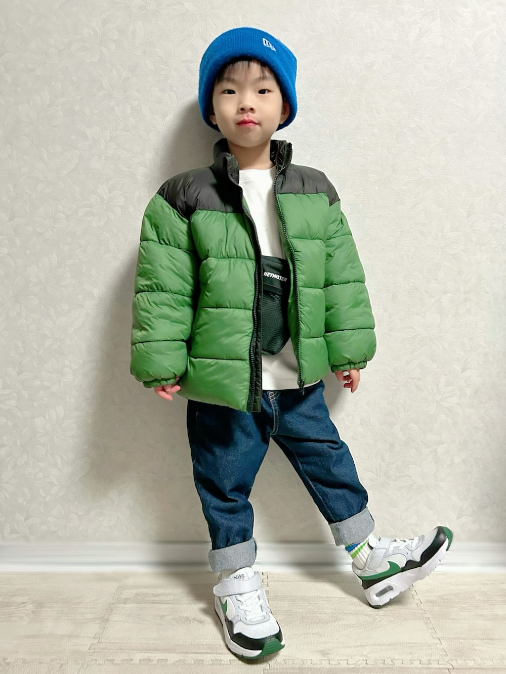 ホワイト系のTシャツ/カットソー、グリーン系のダウンジャケット/コート、ブルー系のデニムパンツを着用したキッズの冬コーディネートの2枚目の写真