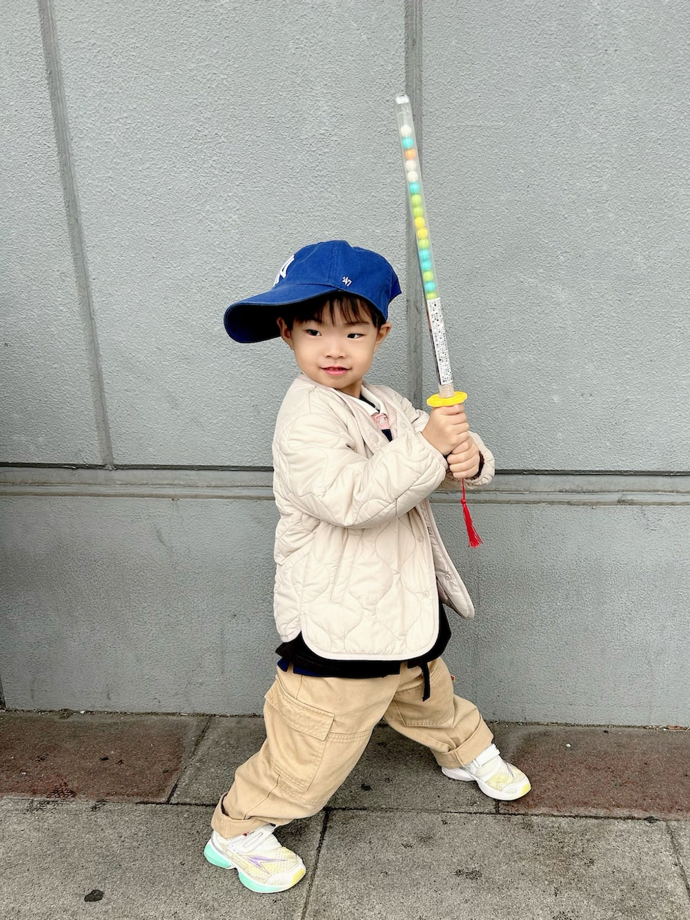 ピンク系のポロシャツ、ブラック系のカーディガン/ボレロ、ベージュ系のカーゴパンツを着用したキッズの冬コーディネートの4枚目の写真