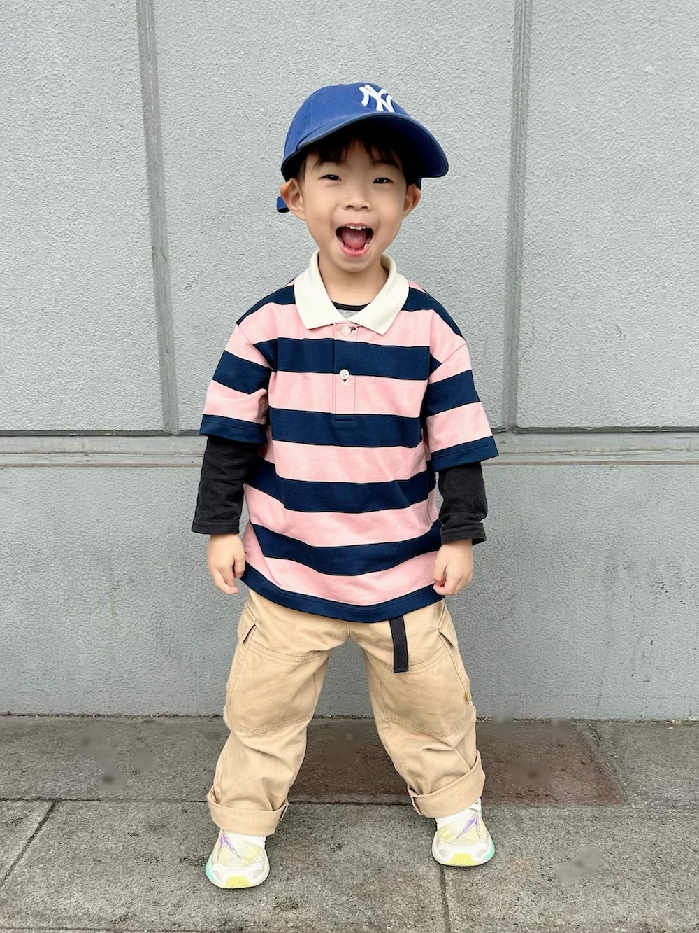 ピンク系のポロシャツ、ベージュ系のカーゴパンツ、ホワイト系のスニーカーを着用したキッズの春コーディネートの2枚目の写真