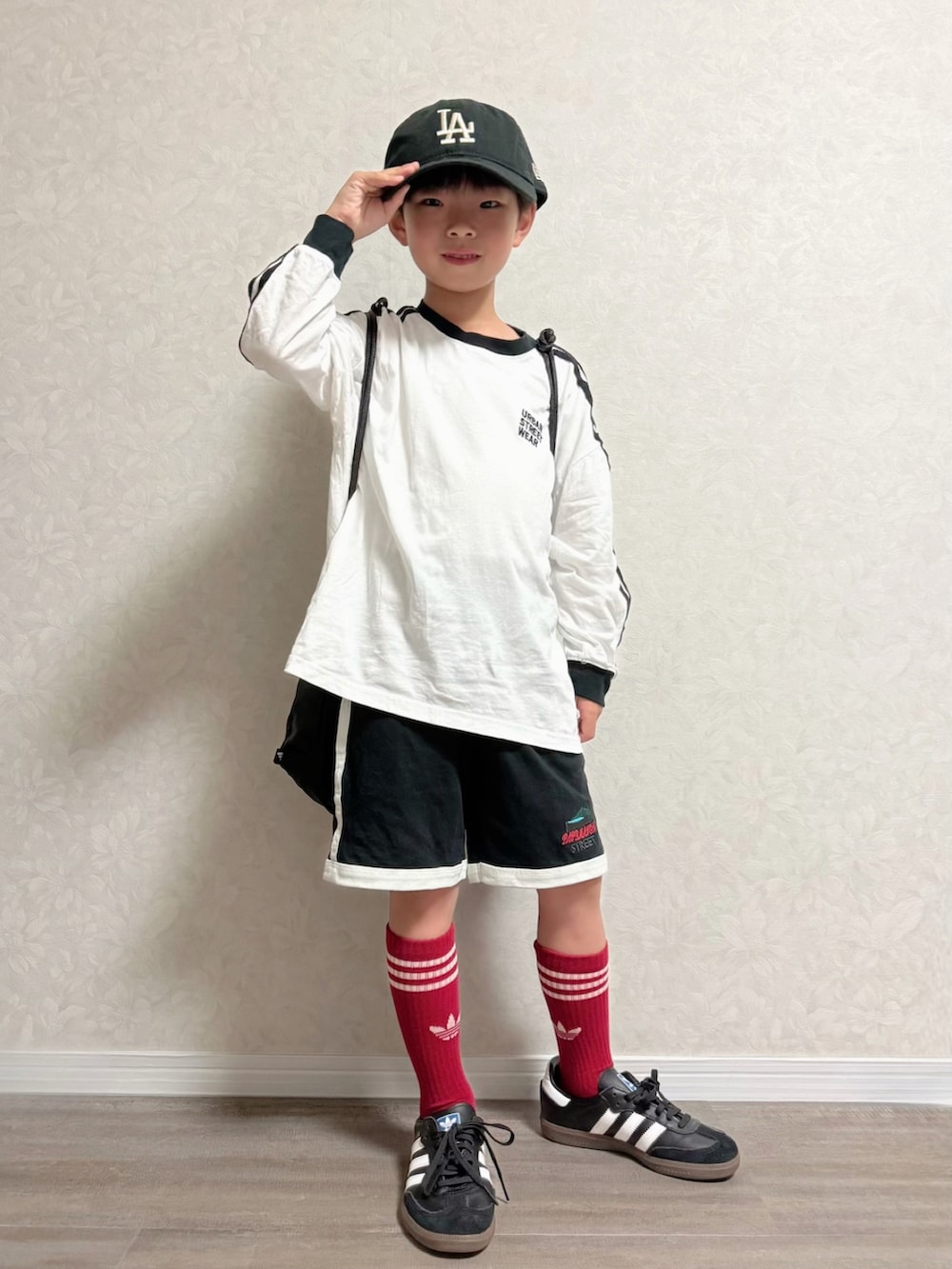 ブラック系のセットアップ、ホワイト系のTシャツ/カットソー、ブラック系のキャップを着用したキッズの秋コーディネートの2枚目の写真