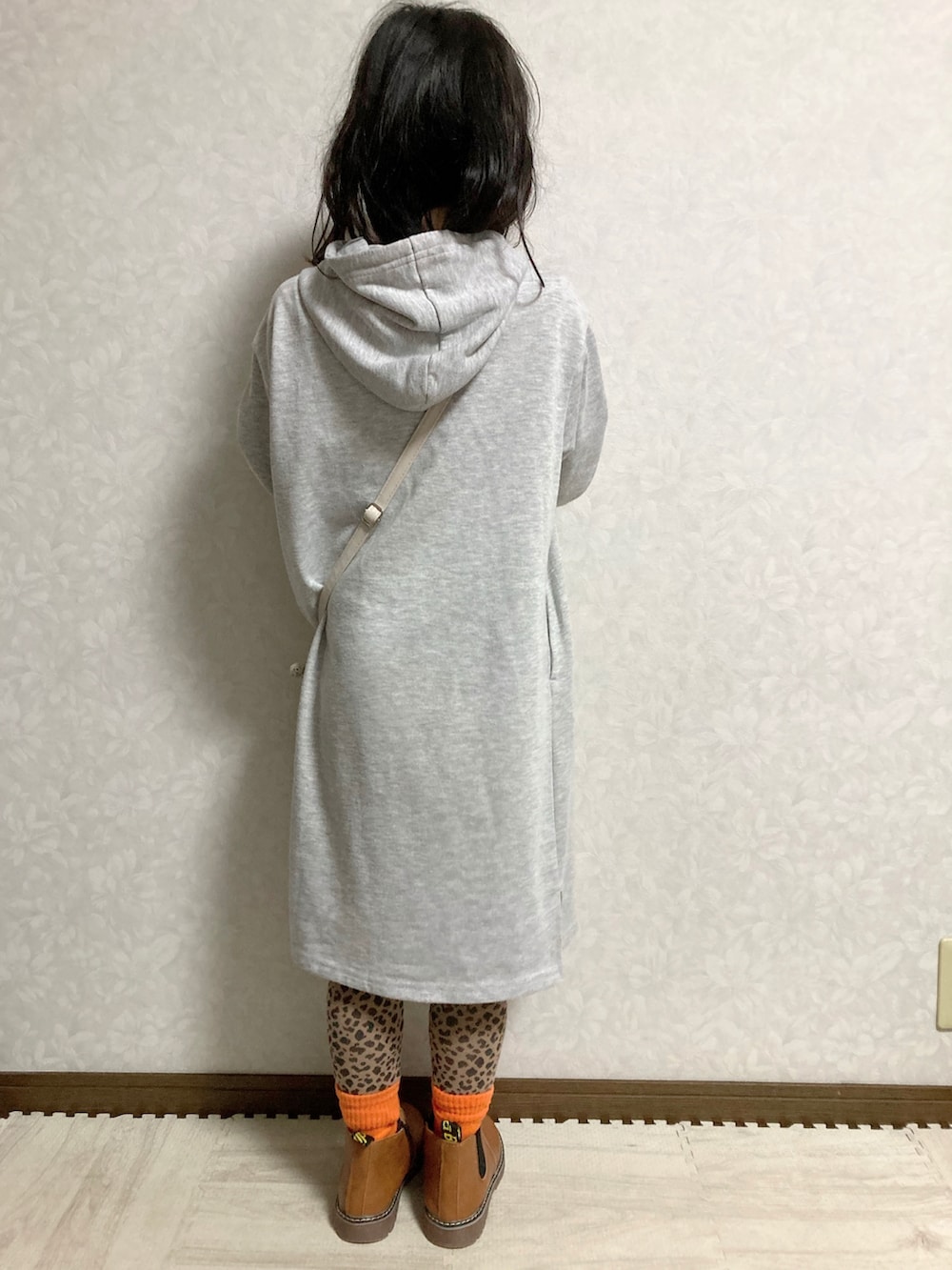 グレー系のワンピース、ホワイト系のショルダーバッグ、ブラウン系のブーツを着用したキッズの冬コーディネートの4枚目の写真