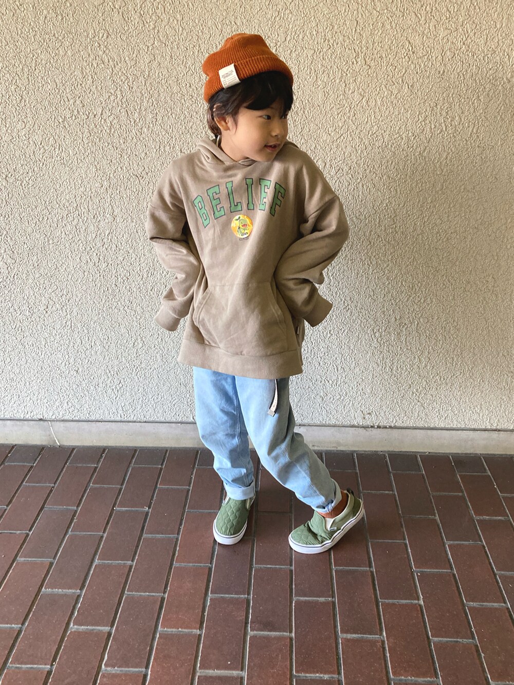 ベージュ系のパーカー、ブルー系のデニムパンツ、グリーン系のスニーカーを着用したキッズの冬コーディネートの2枚目の写真