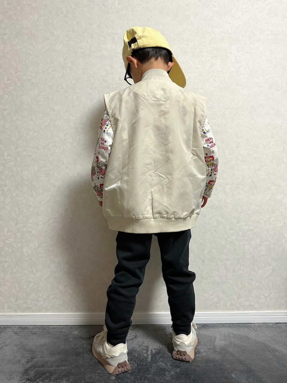 ベージュ系のベスト、ベージュ系のTシャツ/カットソー、ホワイト系のスニーカーを着用したキッズの冬コーディネートの4枚目の写真