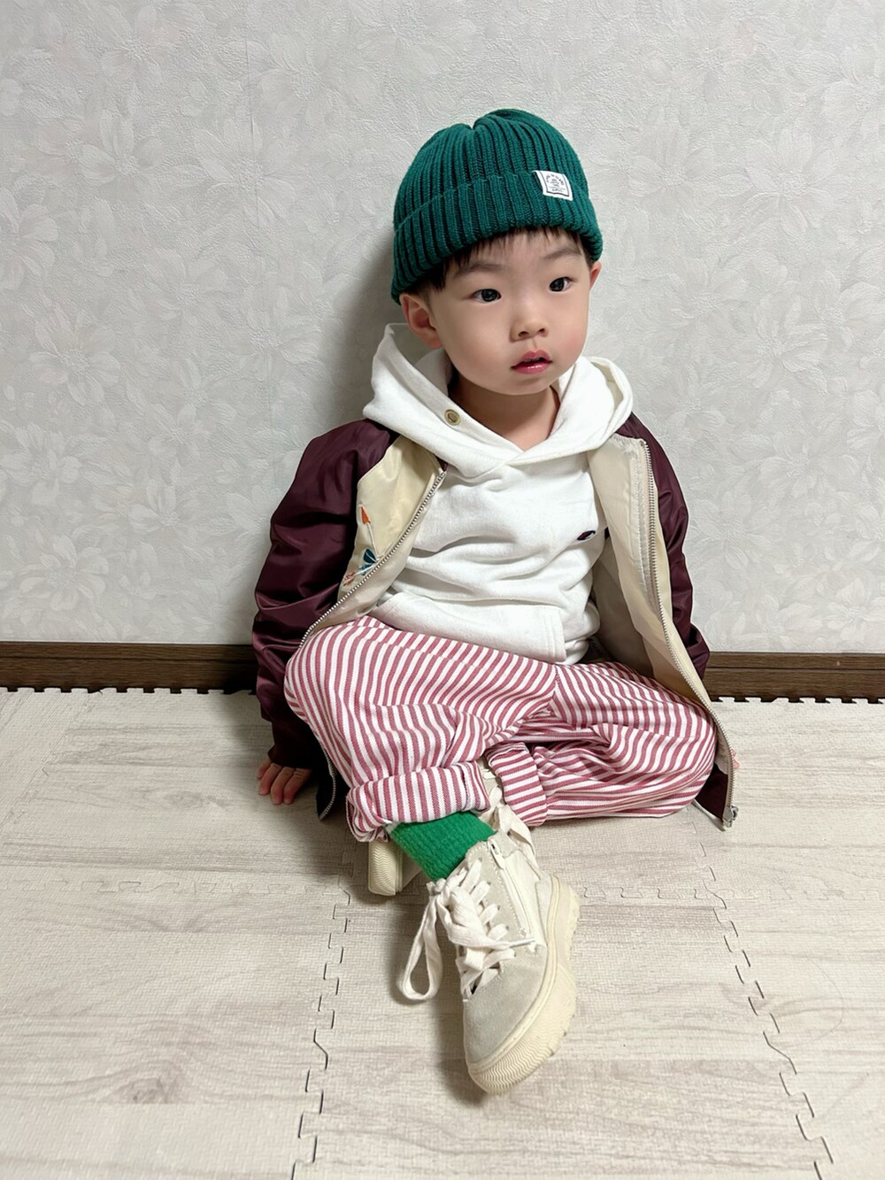 レッド系のブルゾン、ベージュ系のタンクトップ、ホワイト系のパーカーを着用したキッズの春コーディネートの5枚目の写真
