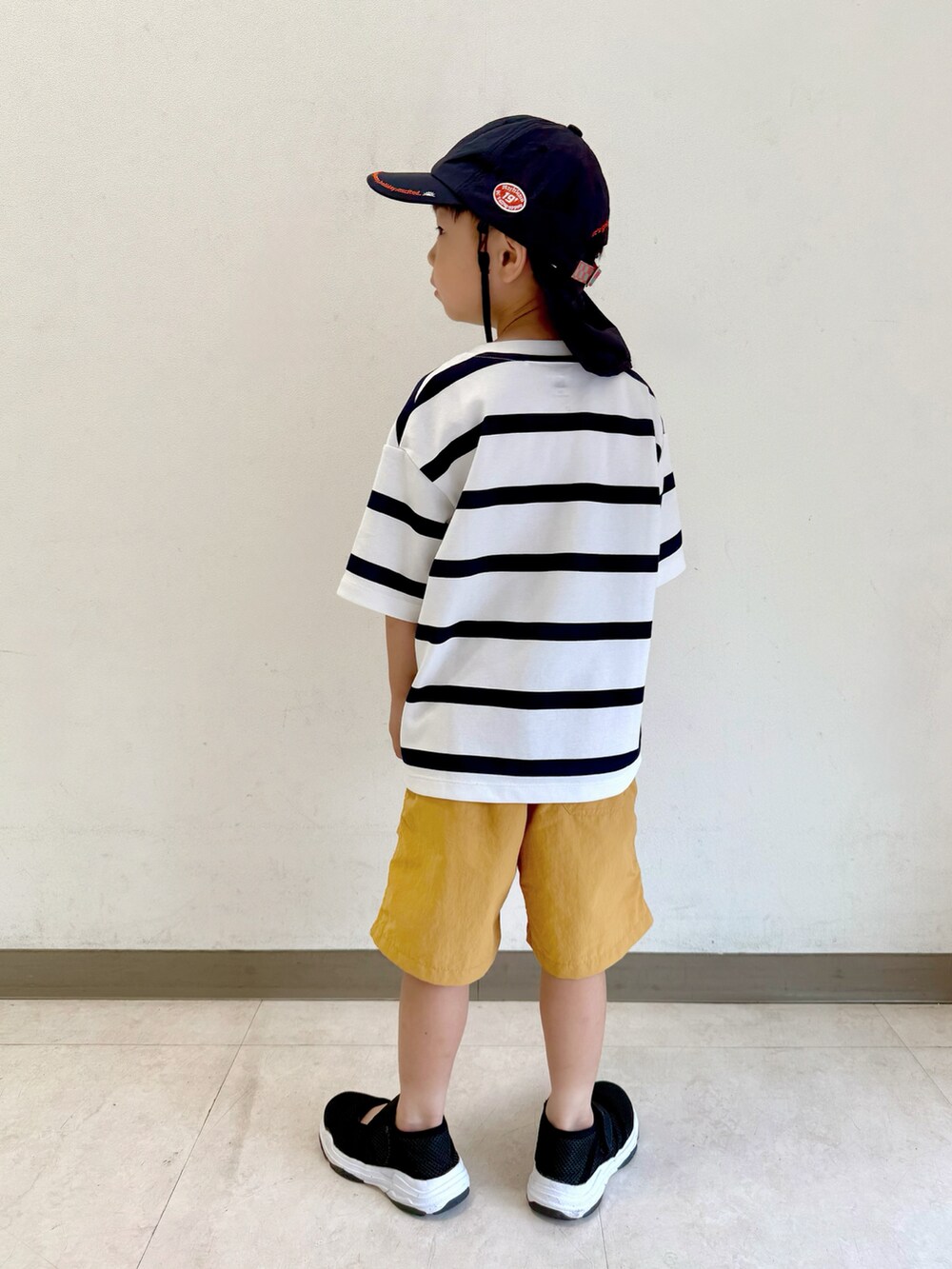 ブラック系のサンダル、ホワイト系のTシャツ/カットソー、ベージュ系のパンツを着用したキッズの夏コーディネートの4枚目の写真