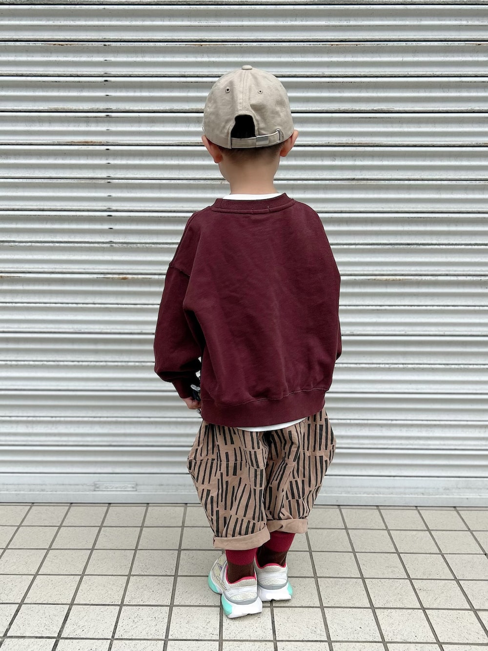 ブラウン系のスウェット、ブラウン系のパンツ、ホワイト系のスニーカーを着用したキッズの秋コーディネートの3枚目の写真