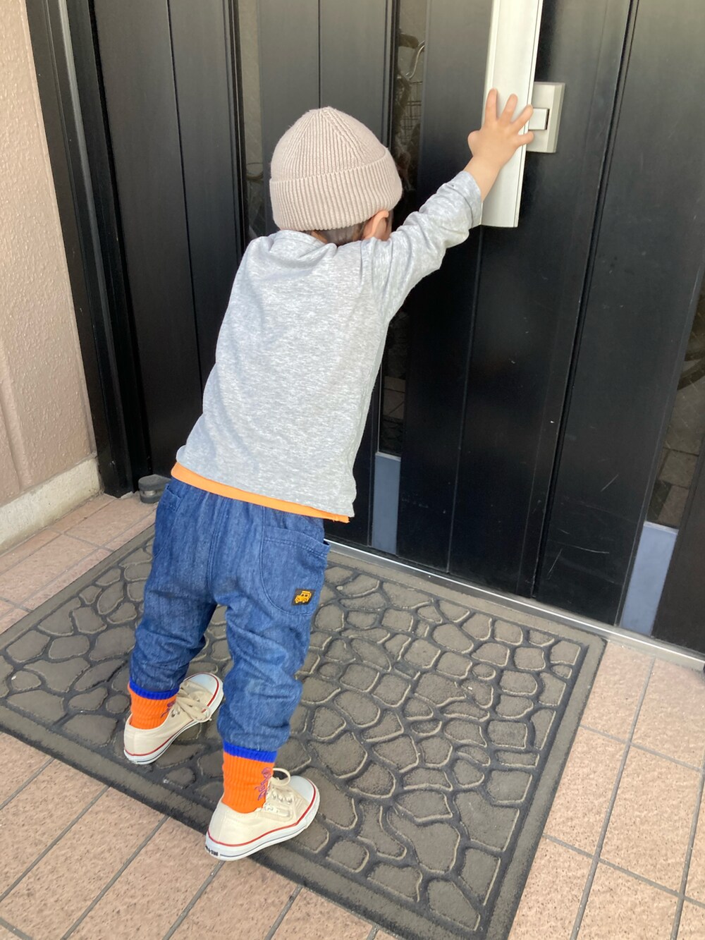 オレンジ系のタンクトップ、グレー系のTシャツ/カットソー、グレー系のナイロンジャケットを着用したキッズの春コーディネートの3枚目の写真