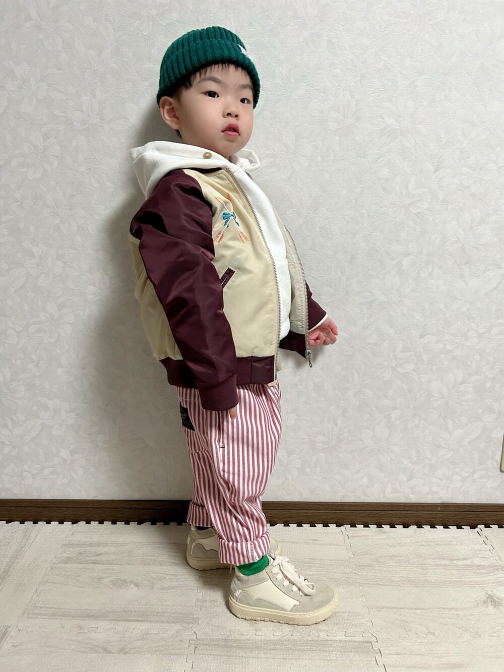 レッド系のブルゾン、ベージュ系のタンクトップ、ホワイト系のパーカーを着用したキッズの春コーディネートの3枚目の写真