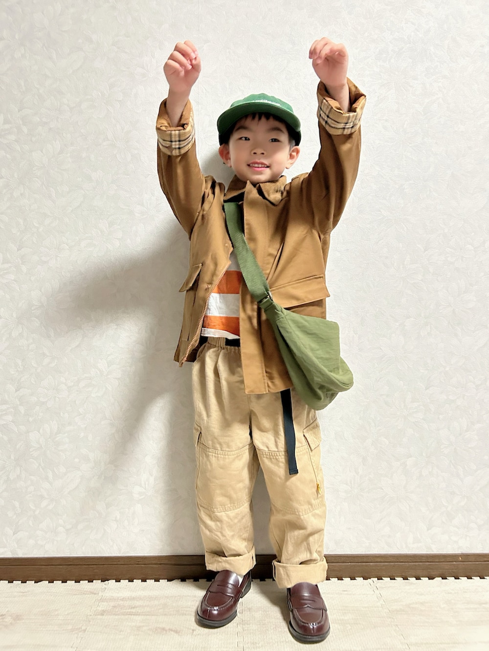 ブラウン系のブルゾン、グリーン系のショルダーバッグ、オレンジ系のTシャツ/カットソーを着用したキッズの秋コーディネートの3枚目の写真