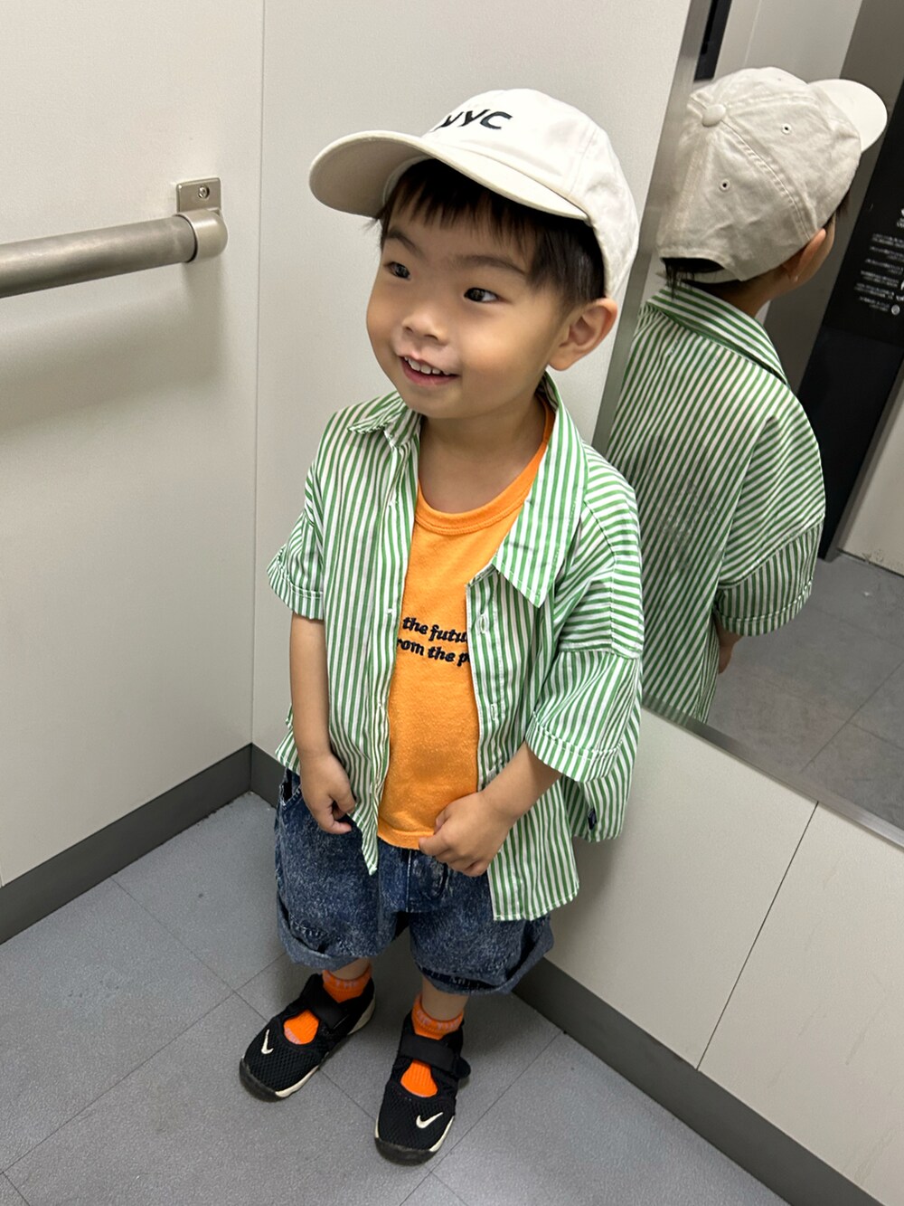 グリーン系のシャツ/ブラウス、オレンジ系のタンクトップ、ブルー系のデニムパンツを着用したキッズの夏コーディネートの4枚目の写真