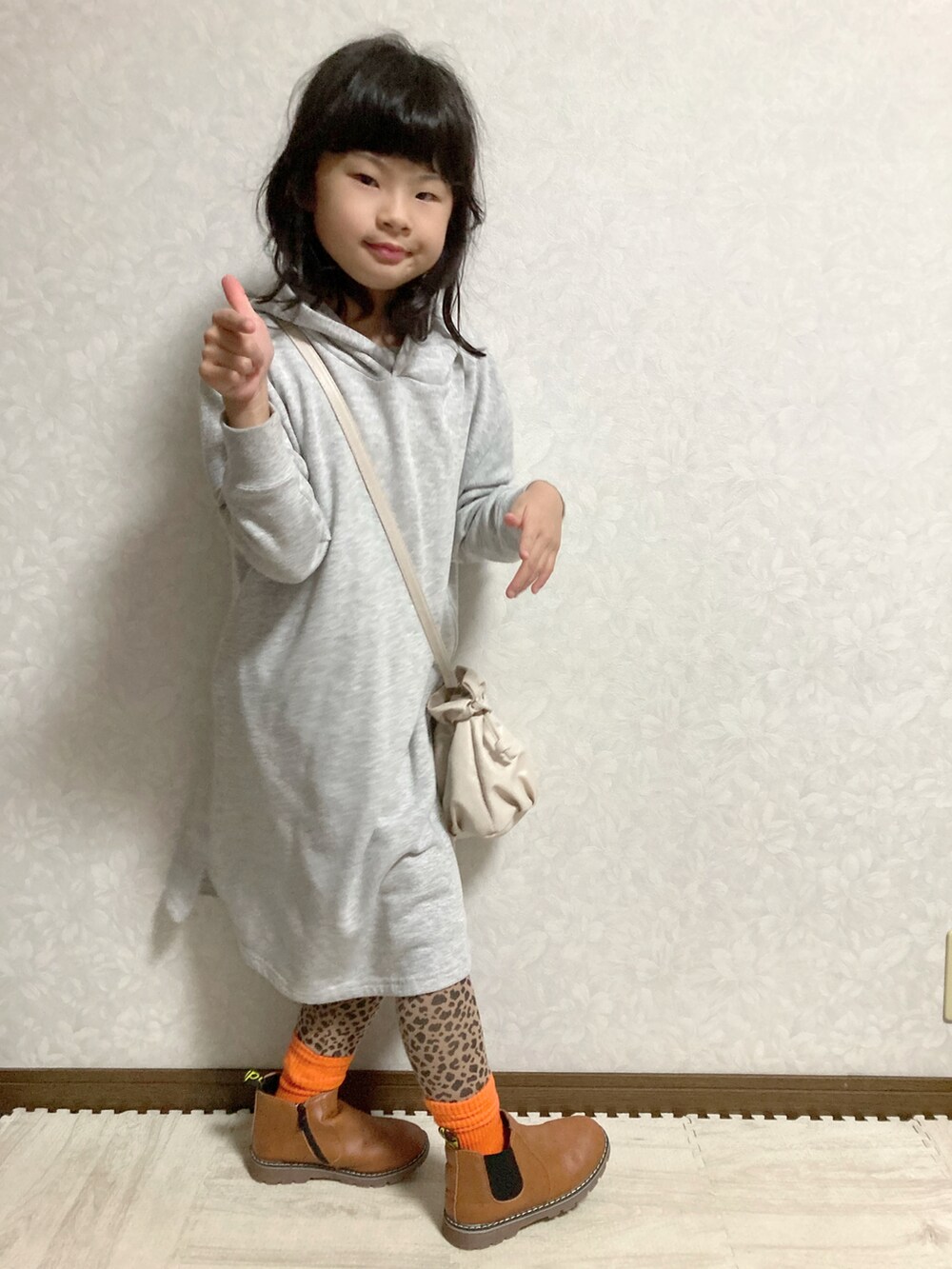 グレー系のワンピース、ホワイト系のショルダーバッグ、ブラウン系のブーツを着用したキッズの冬コーディネートの3枚目の写真