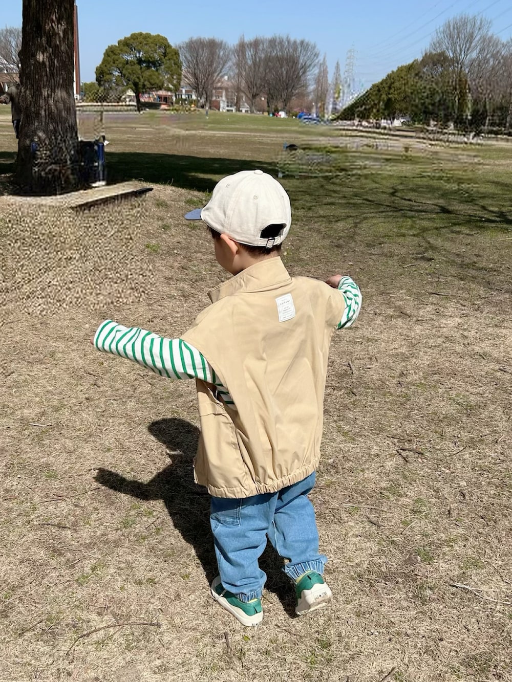 グリーン系のTシャツ/カットソー、ベージュ系のベスト、ブルー系のデニムパンツを着用したキッズの春コーディネートの5枚目の写真