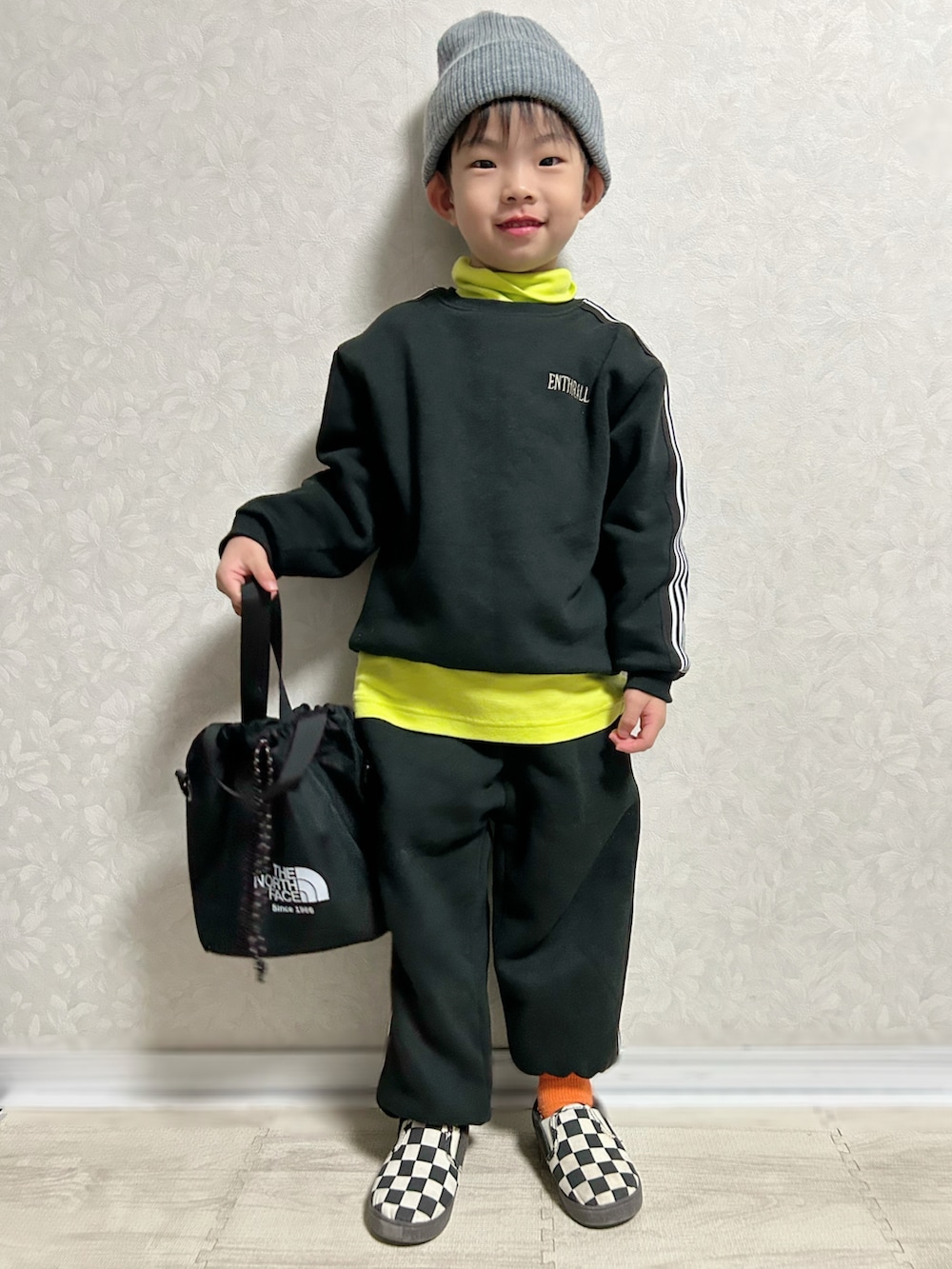 イエロー系のTシャツ/カットソー、ブラック系のセットアップ、ブラック系のショルダーバッグを着用したキッズの冬コーディネートの2枚目の写真