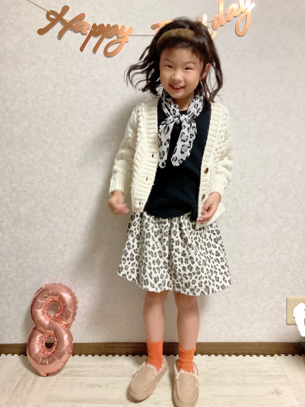 ブラック系のTシャツ/カットソー、ホワイト系のカーディガン/ボレロ、ベージュ系のスカートを着用したキッズの秋コーディネートの3枚目の写真
