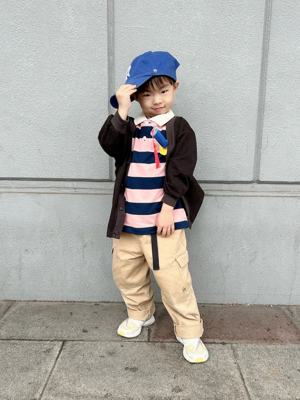 ピンク系のポロシャツ、ブラック系のカーディガン/ボレロ、ベージュ系のカーゴパンツを着用したキッズの冬コーディネートの2枚目の写真