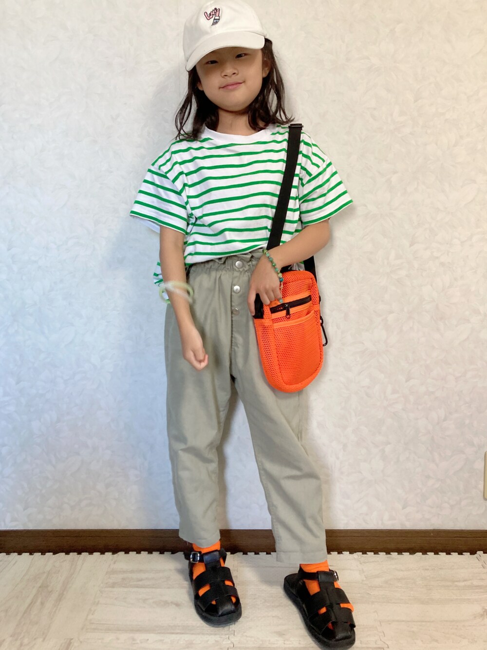 グリーン系のTシャツ/カットソー、グリーン系のパンツ、オレンジ系のショルダーバッグを着用したキッズの夏コーディネートの2枚目の写真