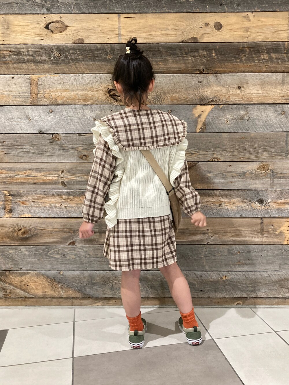 グリーン系のブルゾン、ブラウン系のシャツワンピース、ベージュ系のベストを着用したキッズの冬コーディネートの5枚目の写真