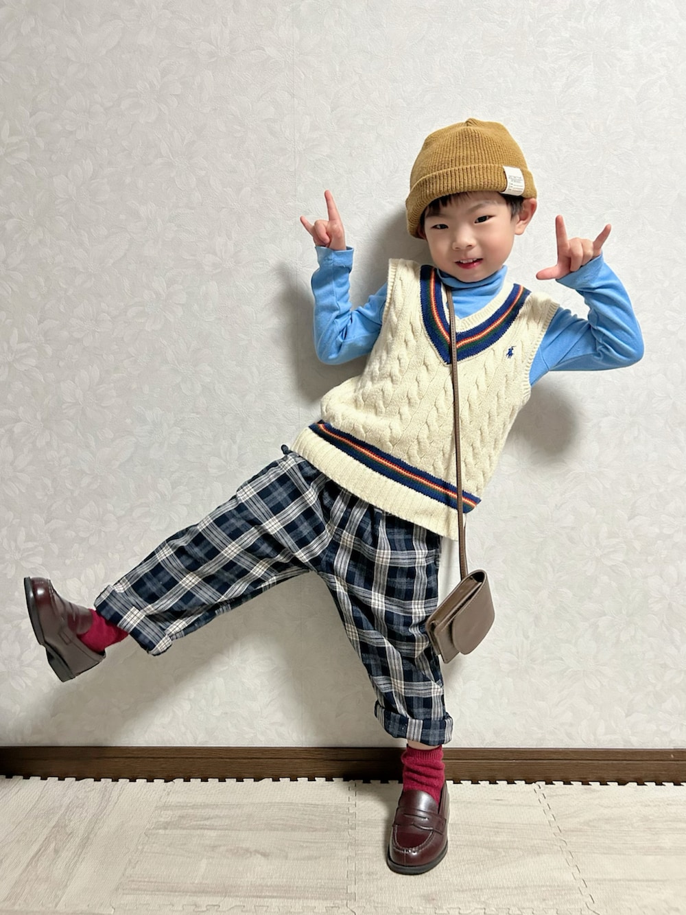 ブルー系のTシャツ/カットソー、ホワイト系のベスト、ブラウン系のショルダーバッグを着用したキッズの冬コーディネートの3枚目の写真