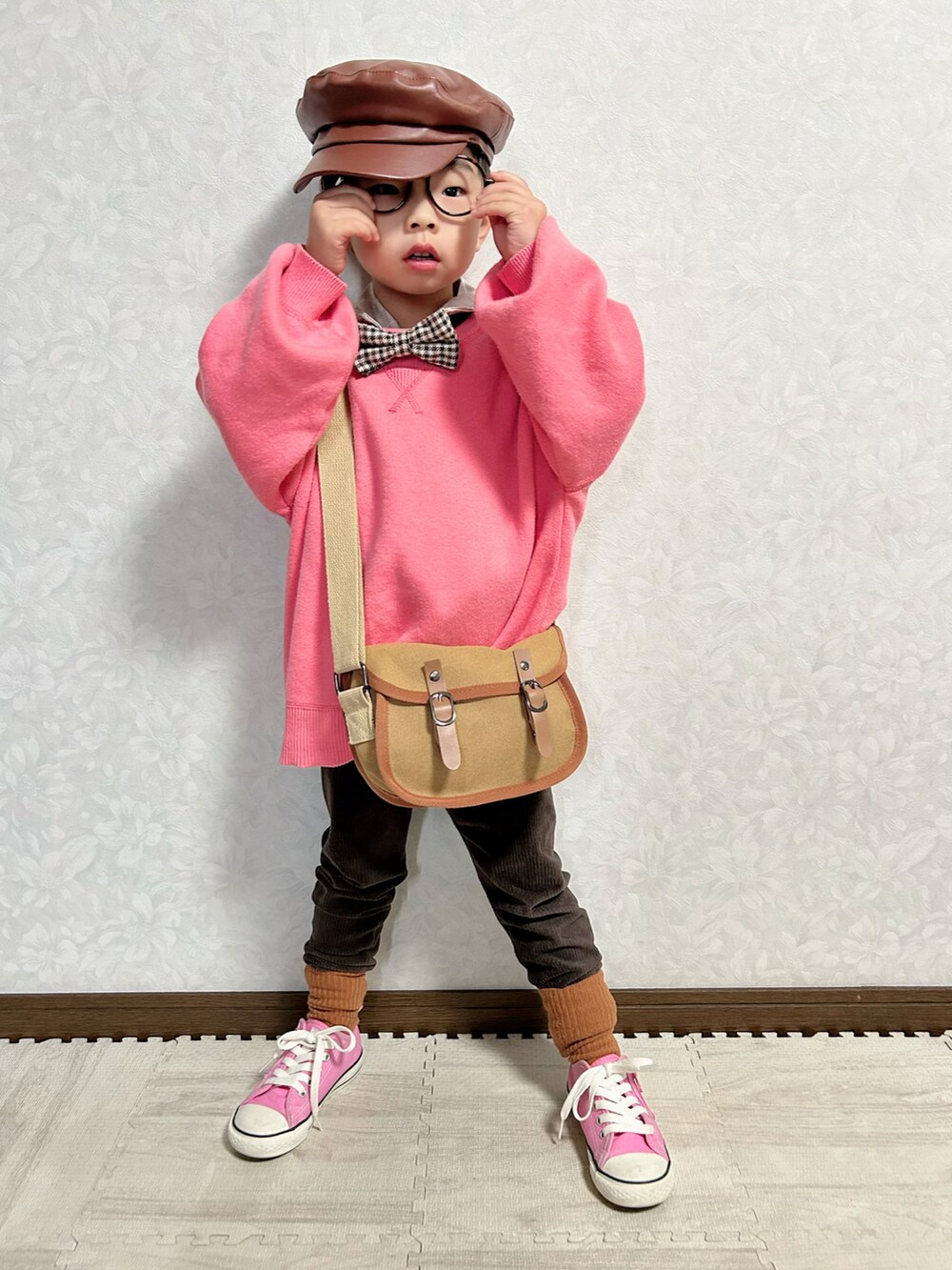 ピンク系のニット/セーター、ベージュ系のセットアップ、ブラウン系のショルダーバッグを着用したキッズの冬コーディネートの4枚目の写真