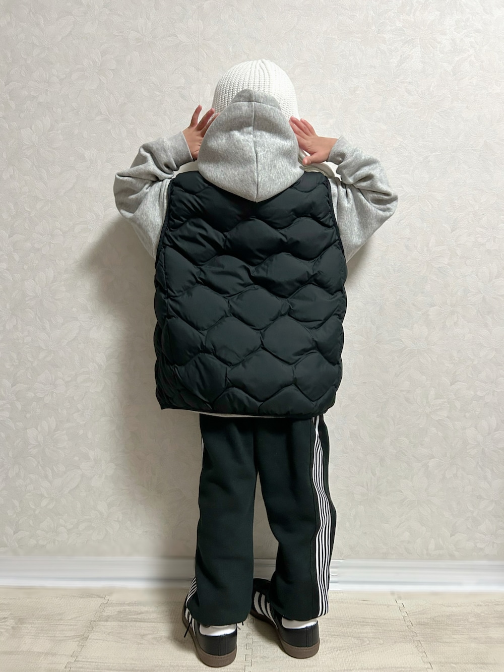 グレー系のパーカー、ブラック系のダウンベスト、ブラック系のセットアップを着用したキッズの冬コーディネートの5枚目の写真