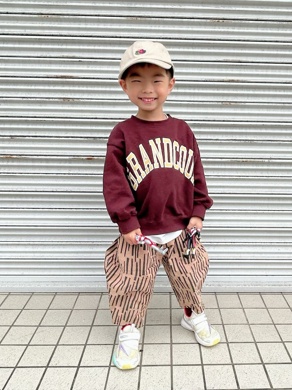 ブラウン系のスウェット、ブラウン系のパンツ、ホワイト系のスニーカーを着用したキッズの秋コーディネートの2枚目の写真