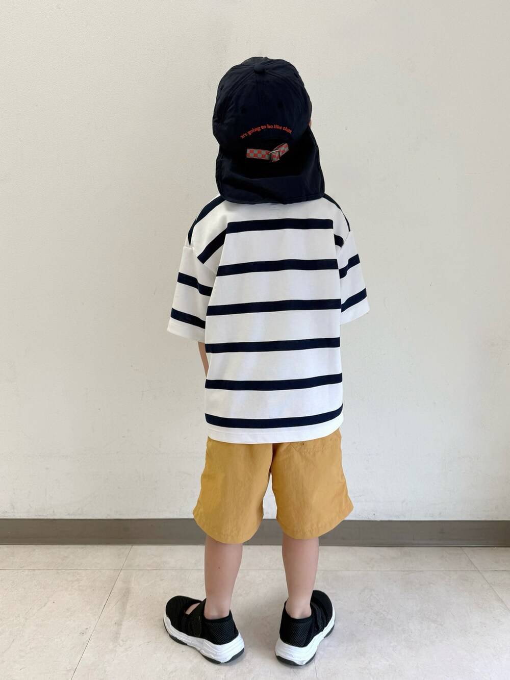 ブラック系のサンダル、ホワイト系のTシャツ/カットソー、ベージュ系のパンツを着用したキッズの夏コーディネートの5枚目の写真