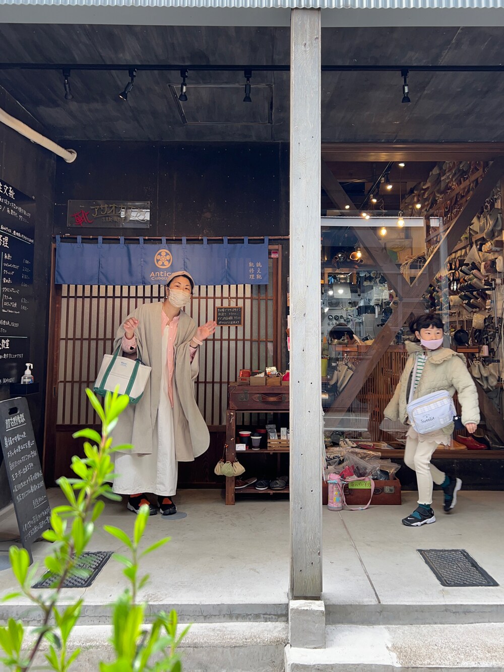 オレンジ系のシャツ/ブラウス、グリーン系のポンチョ、ホワイト系のジャンパースカートを着用したキッズの春コーディネートの2枚目の写真