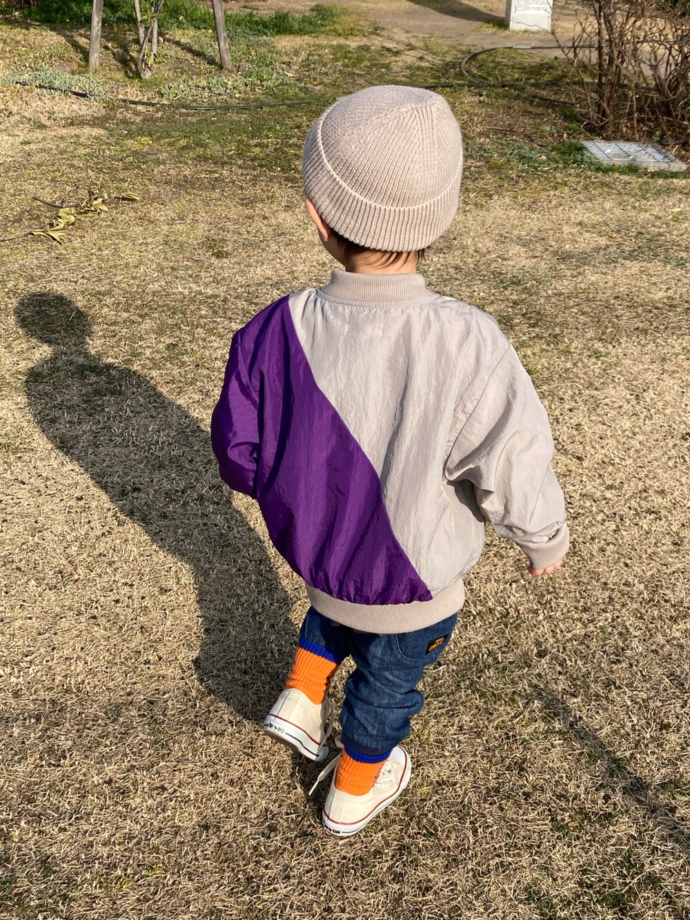 オレンジ系のタンクトップ、グレー系のTシャツ/カットソー、グレー系のナイロンジャケットを着用したキッズの春コーディネートの5枚目の写真