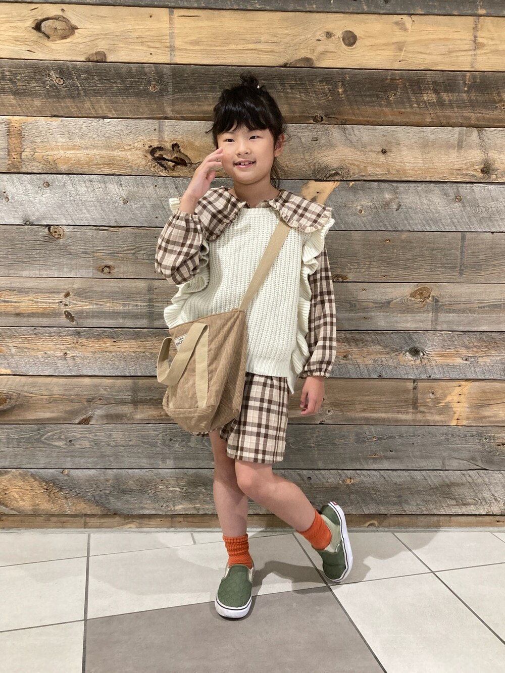 グリーン系のブルゾン、ブラウン系のシャツワンピース、ベージュ系のベストを着用したキッズの冬コーディネートの3枚目の写真