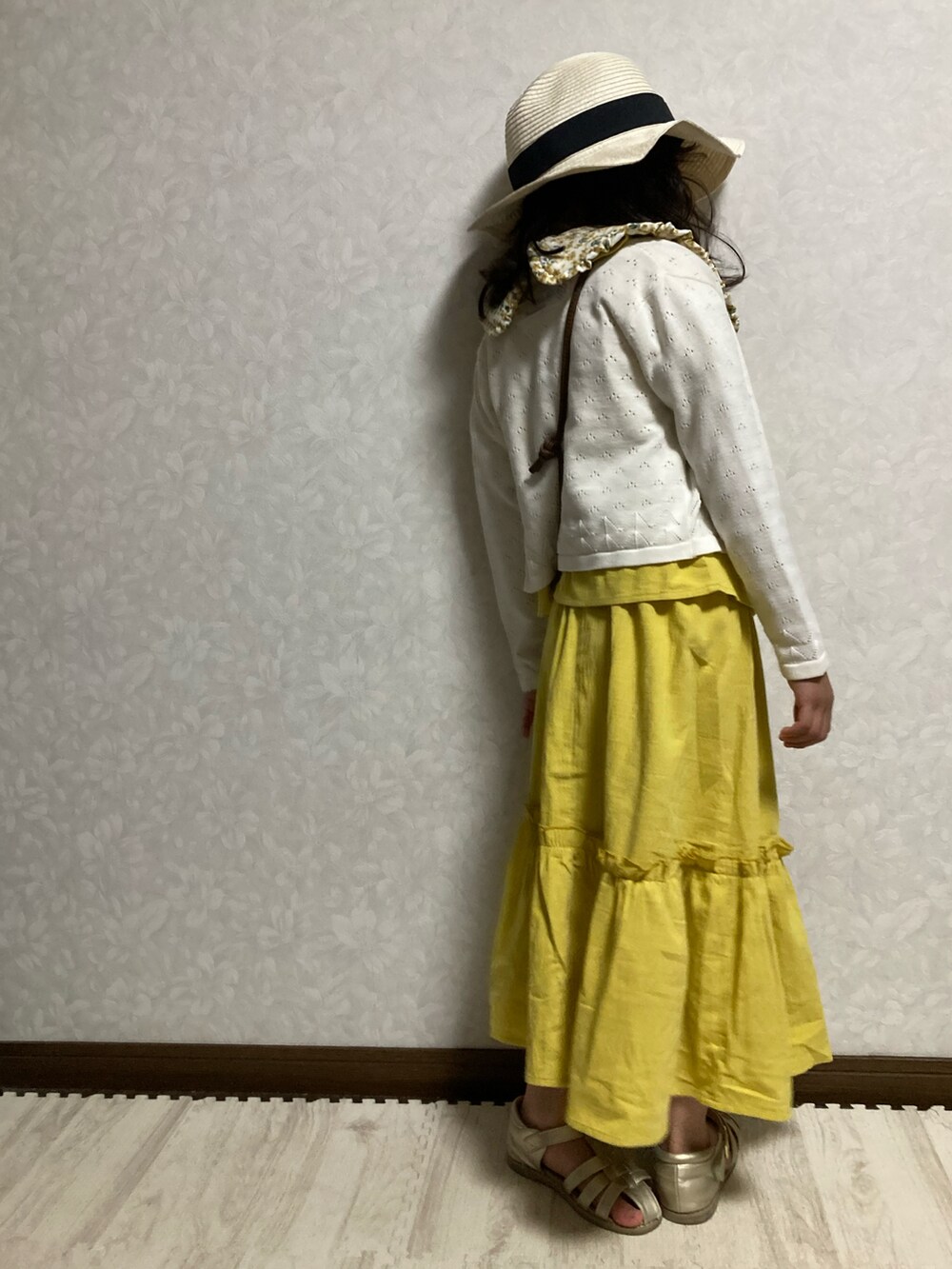 イエロー系のセットアップ、ホワイト系のカーディガン/ボレロ、ブラウン系のショルダーバッグを着用したキッズの春コーディネートの5枚目の写真