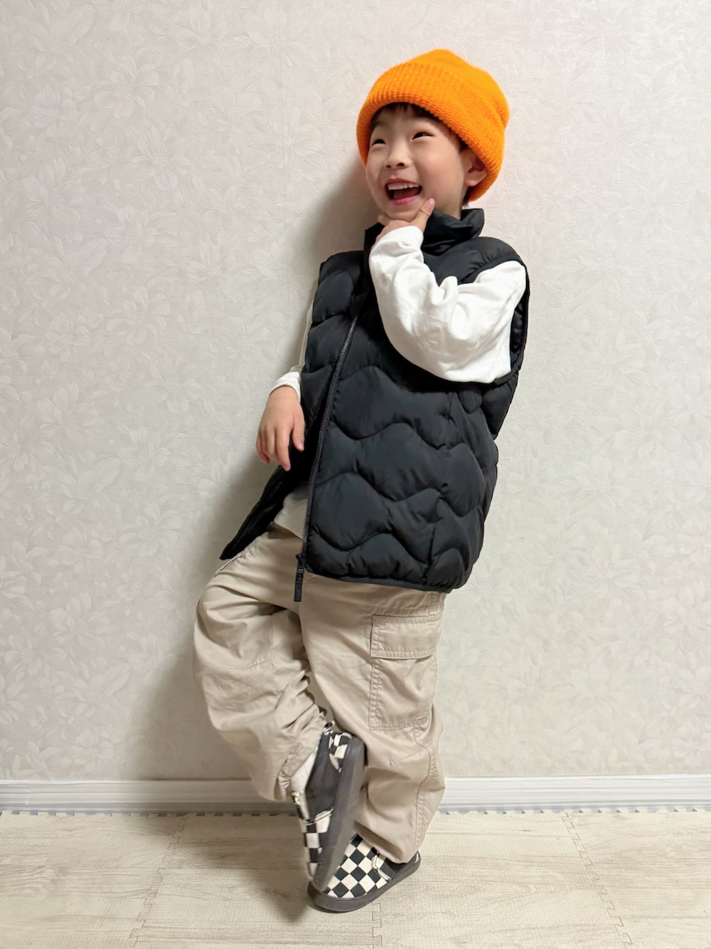 ホワイト系のTシャツ/カットソー、ブラック系のダウンベスト、ベージュ系のカーゴパンツを着用したキッズの春コーディネートの2枚目の写真