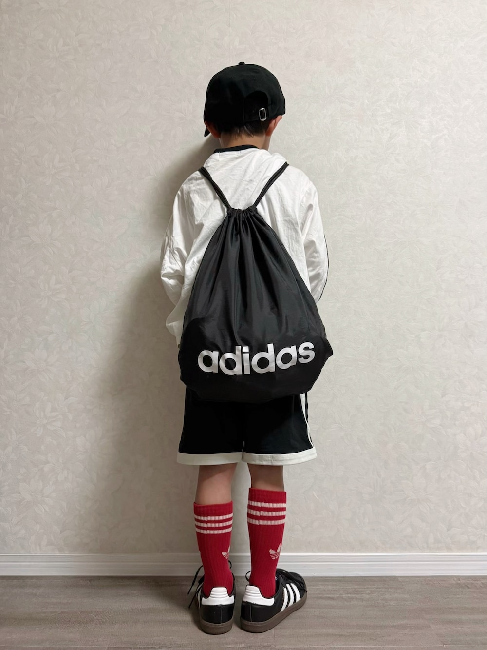 ブラック系のセットアップ、ホワイト系のTシャツ/カットソー、ブラック系のキャップを着用したキッズの秋コーディネートの4枚目の写真