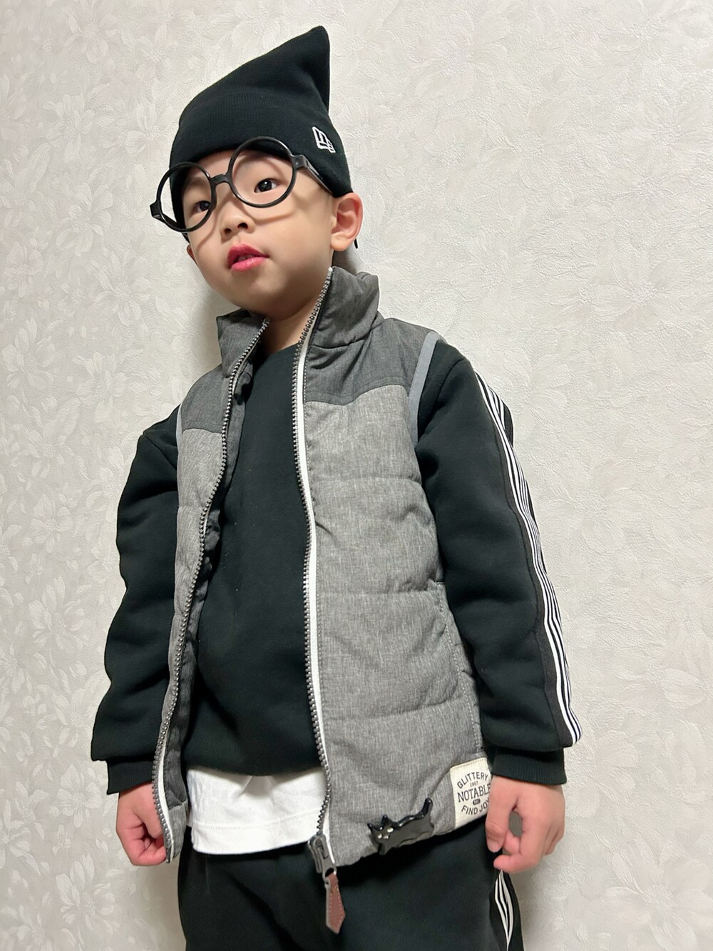 ホワイト系のTシャツ/カットソー、ブラック系のセットアップ、グレー系のダウンベストを着用したキッズの冬コーディネートの4枚目の写真