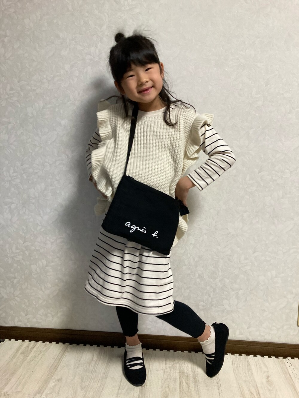 ブラック系のバレエシューズ、ホワイト系のワンピース、ベージュ系のベストを着用したキッズの春コーディネートの2枚目の写真