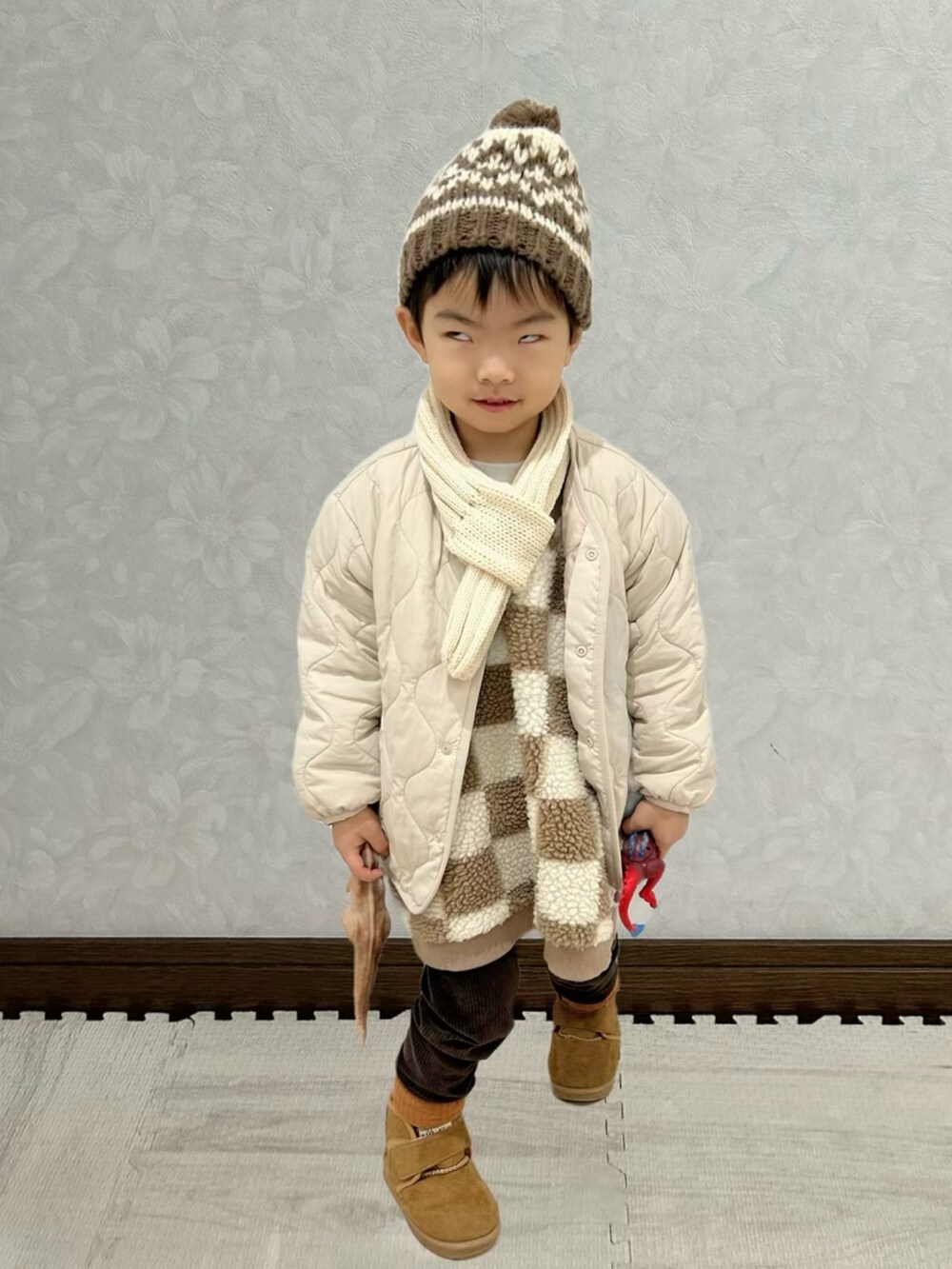 ブラウン系のベスト、ホワイト系のノーカラージャケット、ブラウン系のブーツを着用したキッズの冬コーディネートの3枚目の写真