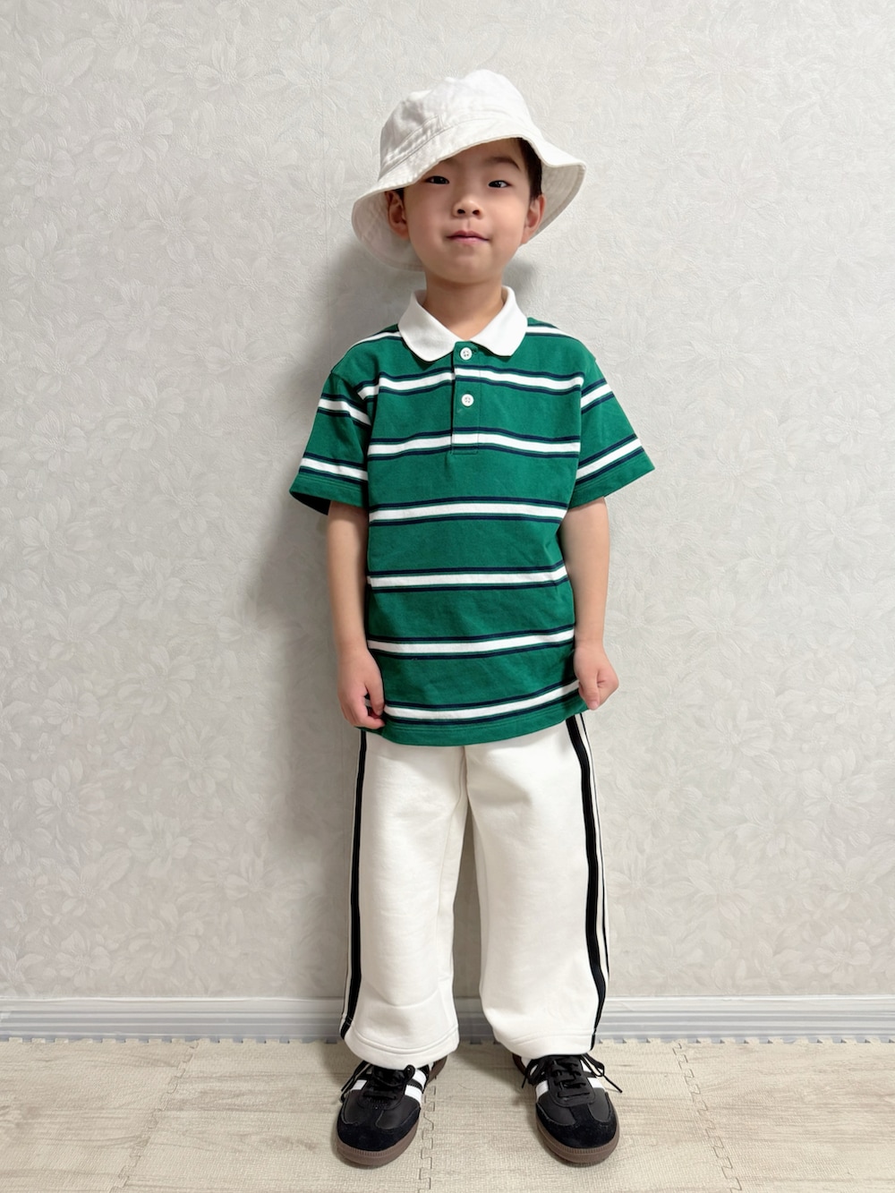 ホワイト系のナイロンジャケット、グリーン系のポロシャツ、ホワイト系のスウェットパンツを着用したキッズの冬コーディネートの3枚目の写真