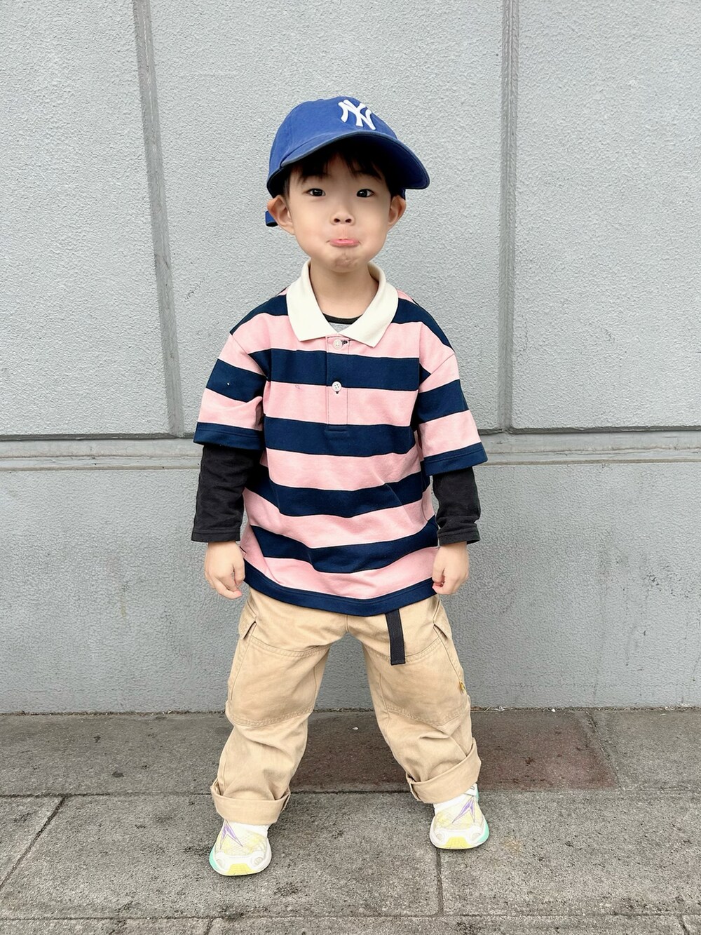 ピンク系のポロシャツ、ベージュ系のカーゴパンツ、ホワイト系のスニーカーを着用したキッズの春コーディネートの3枚目の写真