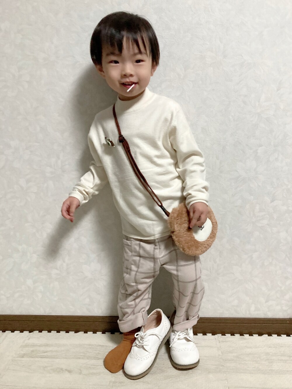 ホワイト系のニット/セーター、ブラウン系のショルダーバッグ、ベージュ系のパンツを着用したキッズの冬コーディネートの3枚目の写真