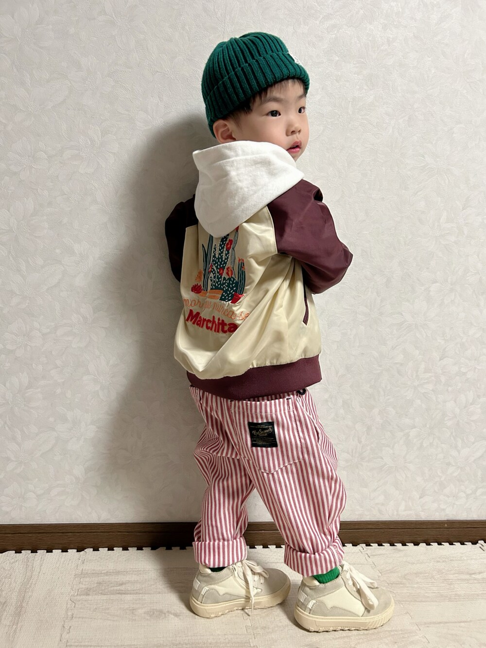 レッド系のブルゾン、ベージュ系のタンクトップ、ホワイト系のパーカーを着用したキッズの春コーディネートの4枚目の写真