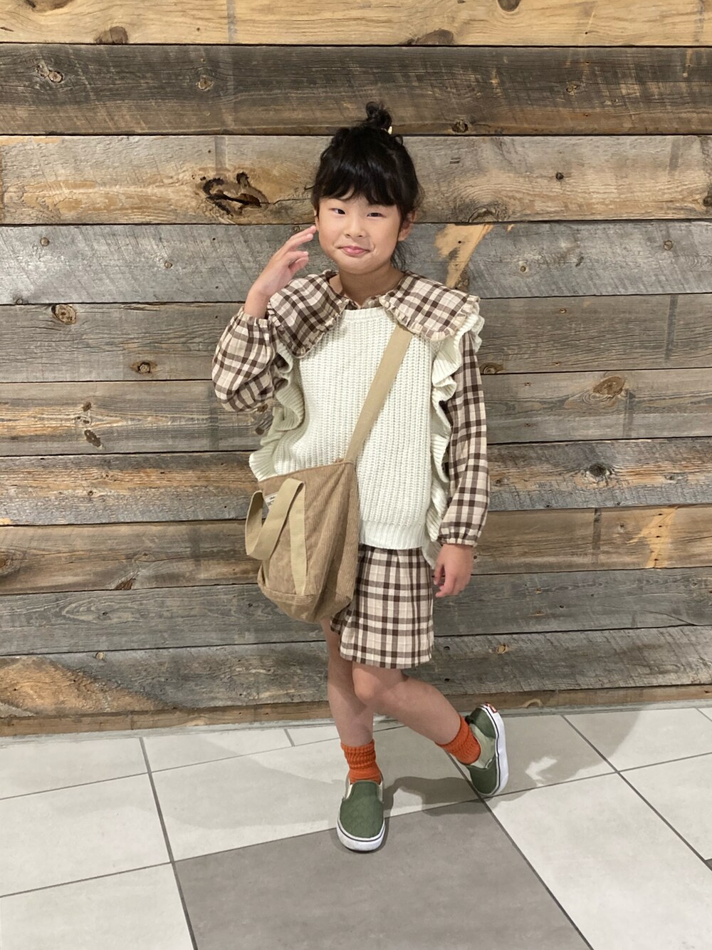 グリーン系のブルゾン、ブラウン系のシャツワンピース、ベージュ系のベストを着用したキッズの冬コーディネートの4枚目の写真
