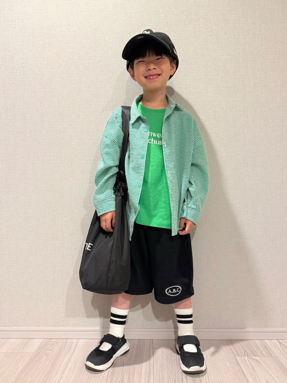 グリーン系のTシャツ/カットソー、ブラック系のセットアップ、ブラック系のサンダルを着用したキッズの春コーディネートの3枚目の写真